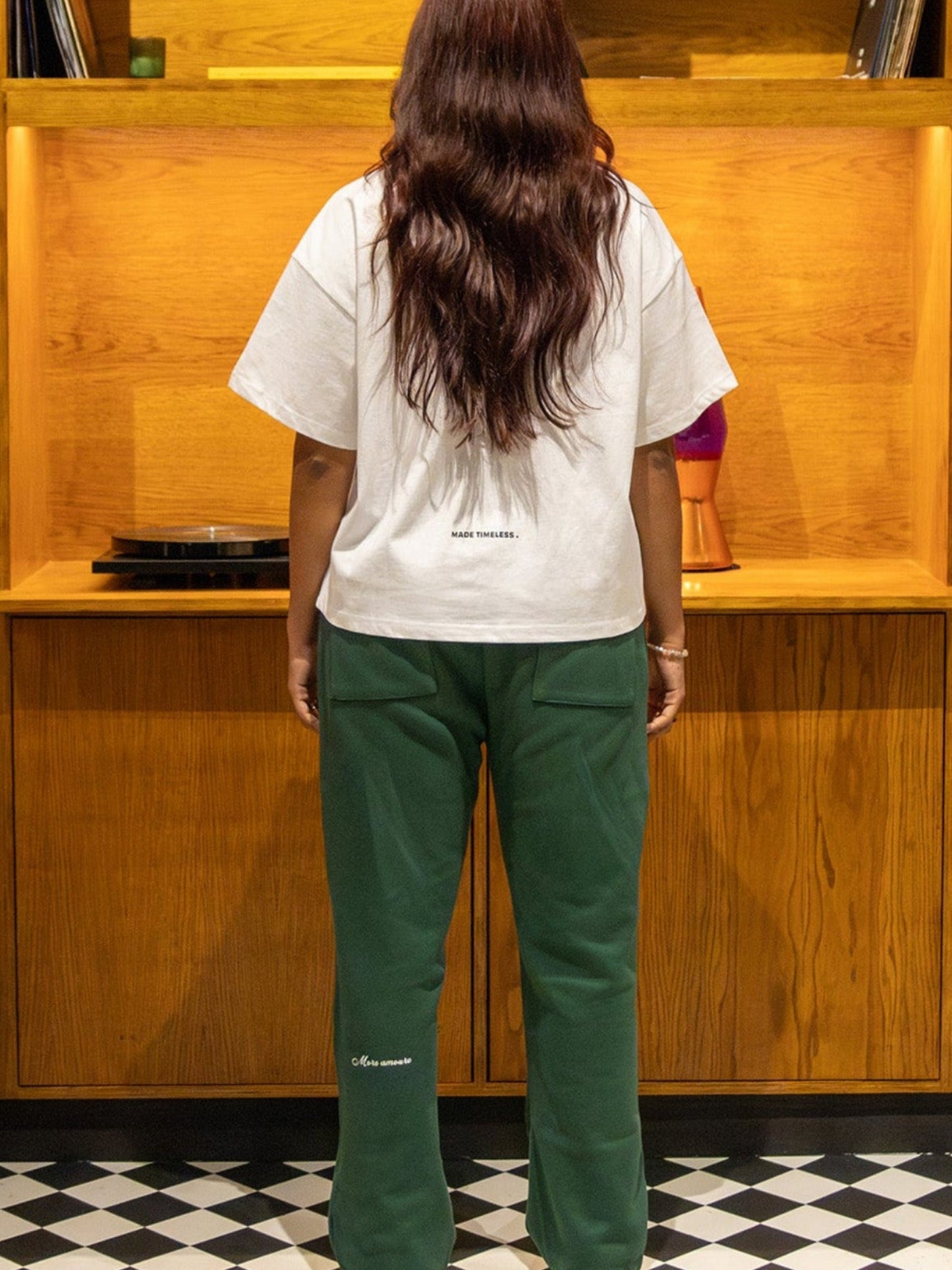 Person standing in a room with wooden bookshelves and vinyl records.