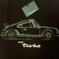 Black t-shirt with a white car graphic and 'More Turbo' text, featuring a tag on a black background.