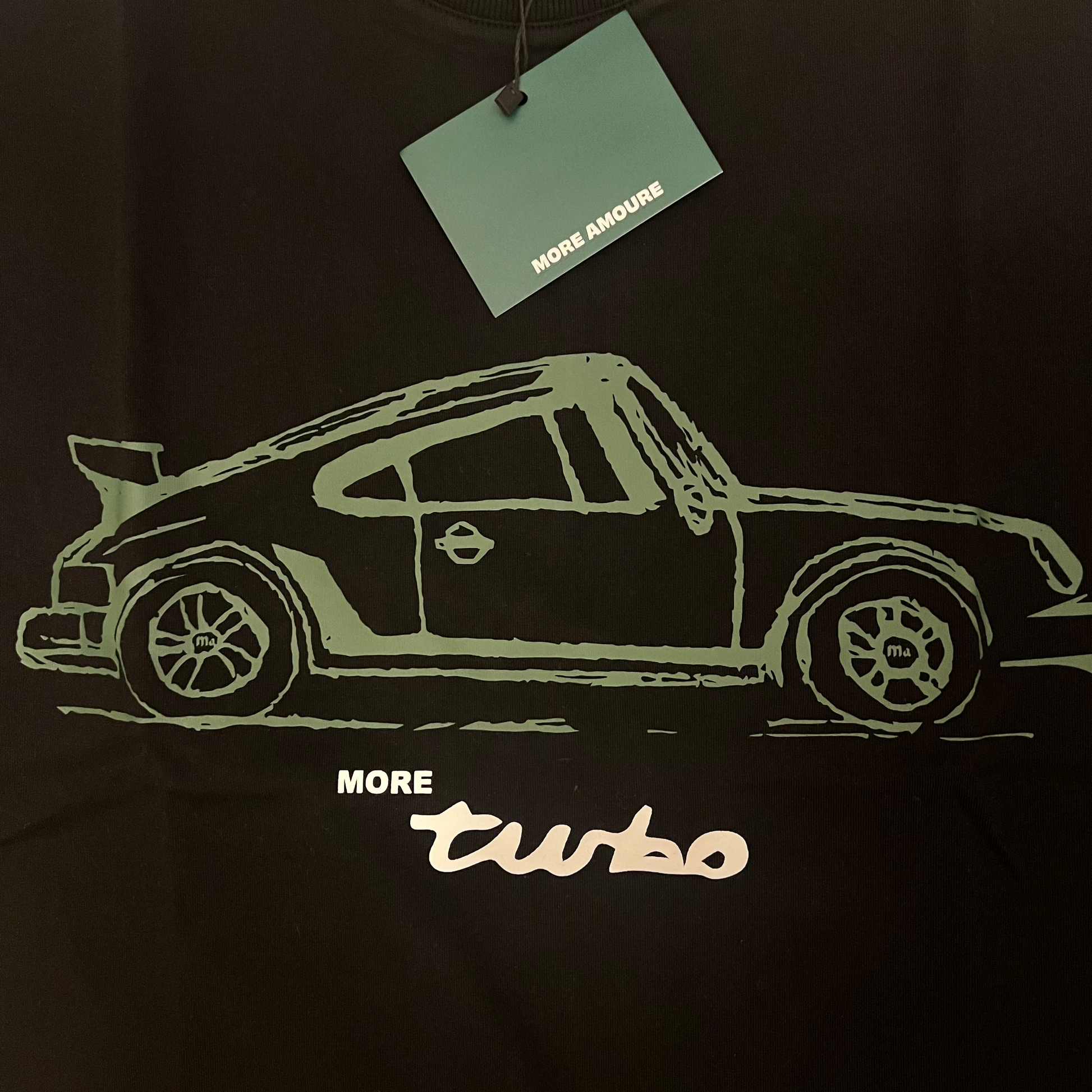 Black t-shirt with a white car graphic and 'More Turbo' text, featuring a tag on a black background.